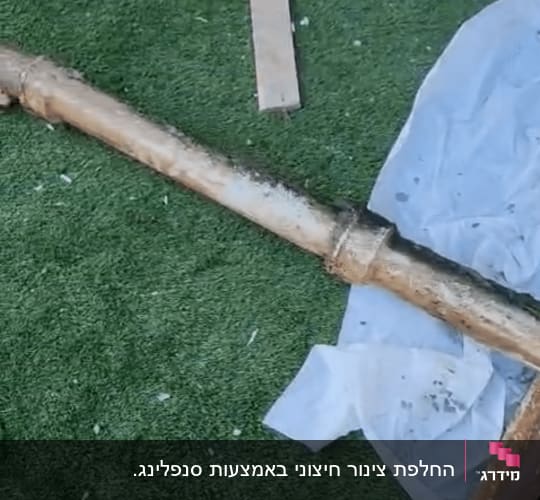 צינור חלוד על דשא מלאכותי עם כלי עבודה
